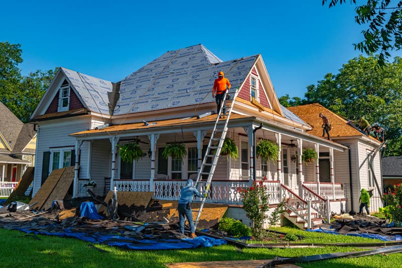 Worker on a ladder at the eaves of a house under renovation
